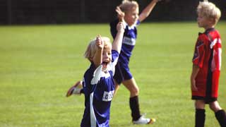 copyright: BilderBox.com Kind in Fußballdress läuft am Sportplatz und jubelt