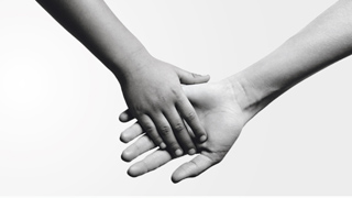 Eine kleine Hand greift nach einer geren Hand.