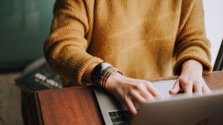 Bildausschnitt: Eine Frau arbeitet an einem Laptop.